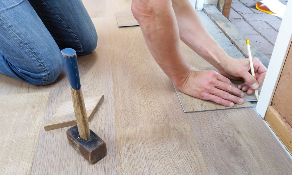 Homme qui pose du parquet pour rénover le sol de son salon