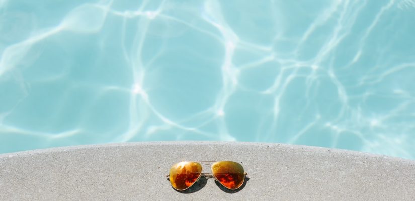 Paire de lunettes de soleil posée au bord d'une piscine