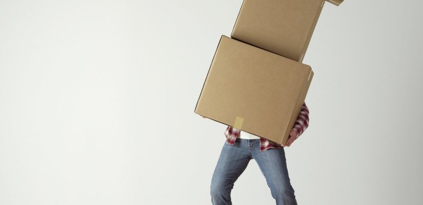 Personne qui soulève trois cartons de déménagement